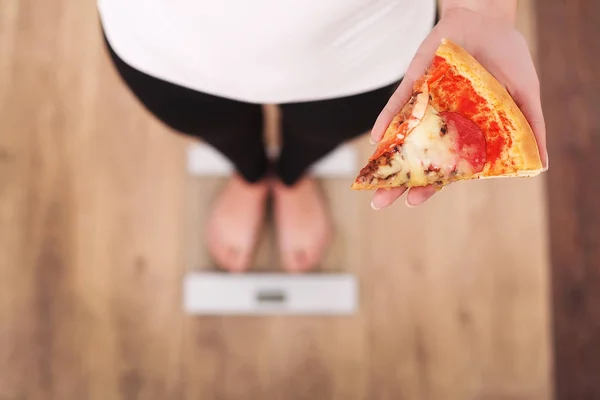 Régime alimentaire. Femme mesurant le poids corporel sur l'échelle de pesée tenant la pizza. Les bonbons sont malsains malbouffe. Régime alimentaire, saine alimentation, mode de vie. Perte de poids. Obésité. Vue du dessus — Photo