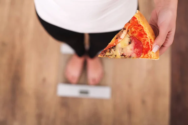 Dieta. Mujer que mide el peso corporal en la balanza de pesaje que sostiene la pizza — Foto de Stock