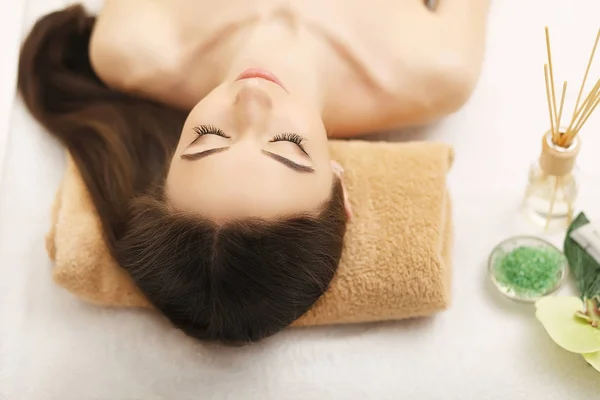 Bella giovane donna ottenere massaggio facciale sdraiato sul divano . — Foto Stock