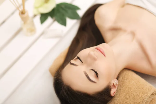 Krásná mladá žena dostává masáž obličeje ležet na gauči. — Stock fotografie