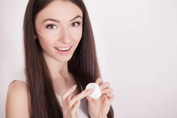 woman with healthy face applying cosmetic cream under the eyes