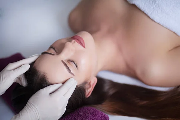 Hermosa joven mujer relajante con masaje facial en el spa de belleza — Foto de Stock