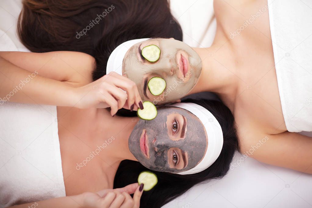 Comic young sisters after shower making mask with cucumber