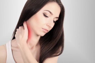 Bir kadınla bir ağrılı boyun omuz kırmızı, boyalı, gri bir arka duvarına vurgulanan acı. Genç güzel kadın. Tahriş Traumatologist Osteochondrosis