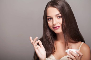 kadın sağlıklı yüzü gözlerimin altında kozmetik krem uygulamak