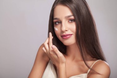 kadın sağlıklı yüzü gözlerimin altında kozmetik krem uygulamak