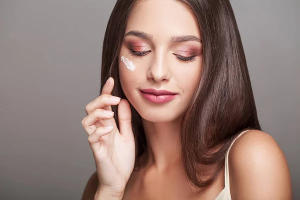 Mujer con cara sana aplicando crema cosmética debajo de los ojos — Foto de Stock