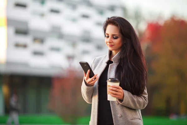 Coffee on the go. Beautiful young woman holding coffee cup and s