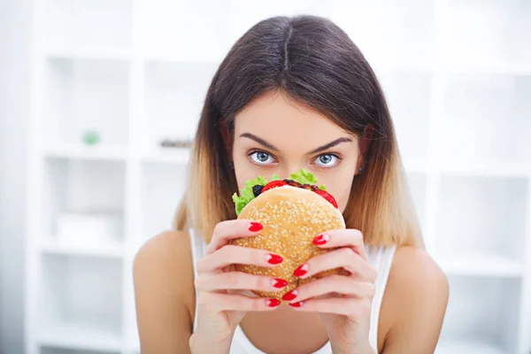 Dieta. Una joven sosteniendo una hamburguesa en una cinta métrica. Una chica. — Foto de Stock