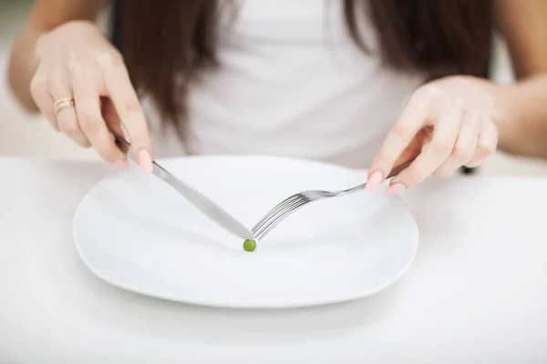 Transtorno alimentar. Menina está segurando um prato e tentando colocar uma ervilha — Fotografia de Stock