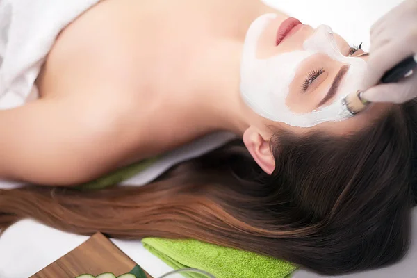 People, beauty, spa, cosmetology and skincare concept - close up of beautiful young woman lying with closed eyes and cosmetologist applying facial mask by brush in spa — Stock Photo, Image