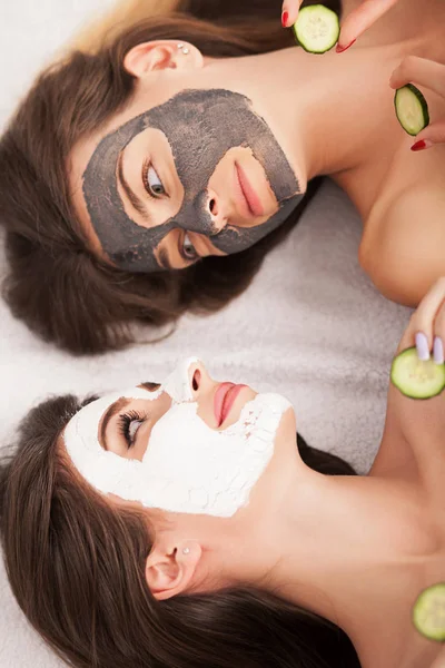 Домашній спа-центр. Дві жінки тримають шматочки огірка на обличчях брешуть — стокове фото