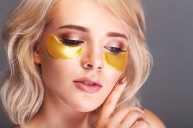 Yama gözlerinin altında. Güzel bir kadın yüzü ile altın hidrojel Patche