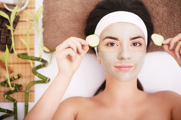 Mulher bonita está recebendo máscara de barro facial no spa, deitado — Fotografia de Stock