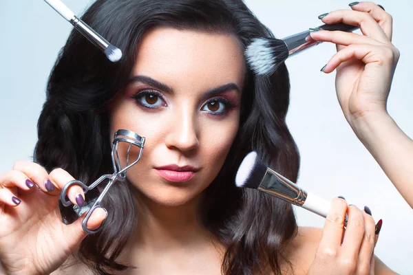 Närbild av ung kvinna ansikte med alla typer av make-up verktyg - b — Stockfoto