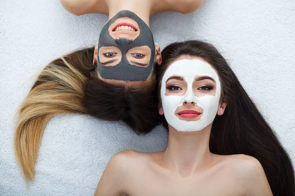 Home spa. Two women holding pieces of cucumber on their faces ly — Stock Photo, Image