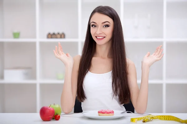 Diéta koncepció. Fiatal nő közötti választás gyümölcsök és édességek — Stock Fotó