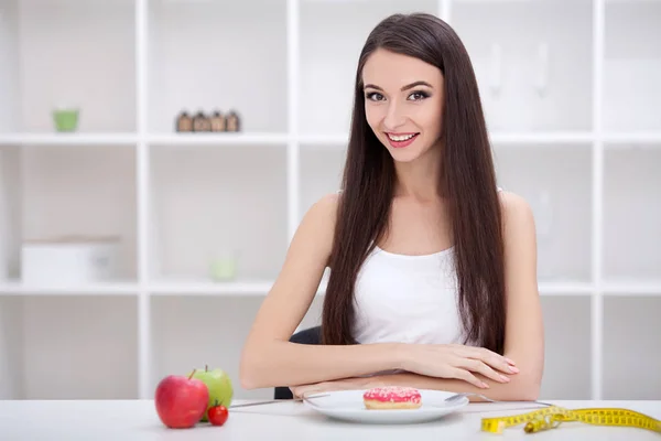 Conceito de dieta. Jovem mulher escolhendo entre frutas e doces — Fotografia de Stock