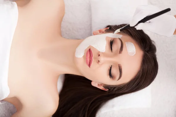 Vacker kvinna med kosmetiska mask på ansiktet. tjej får behandling — Stockfoto