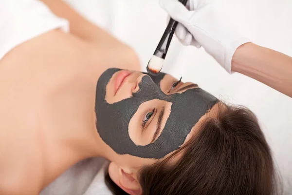 Ett spa. Attraktiv rolig kvinna med en lermask i ansiktet. — Stockfoto