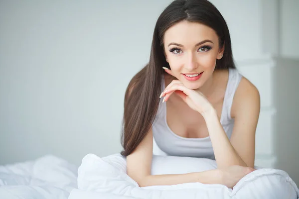 一个年轻的女人睡在白色的床上, 衣服在家里的床上。重新 — 图库照片