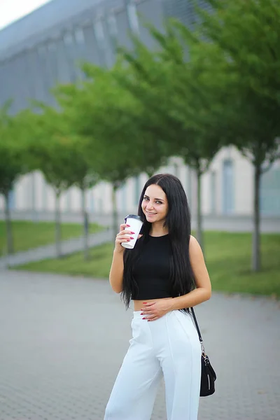 Jonge mooie zakenvrouw drinkt koffie in de buurt van naast office — Stockfoto