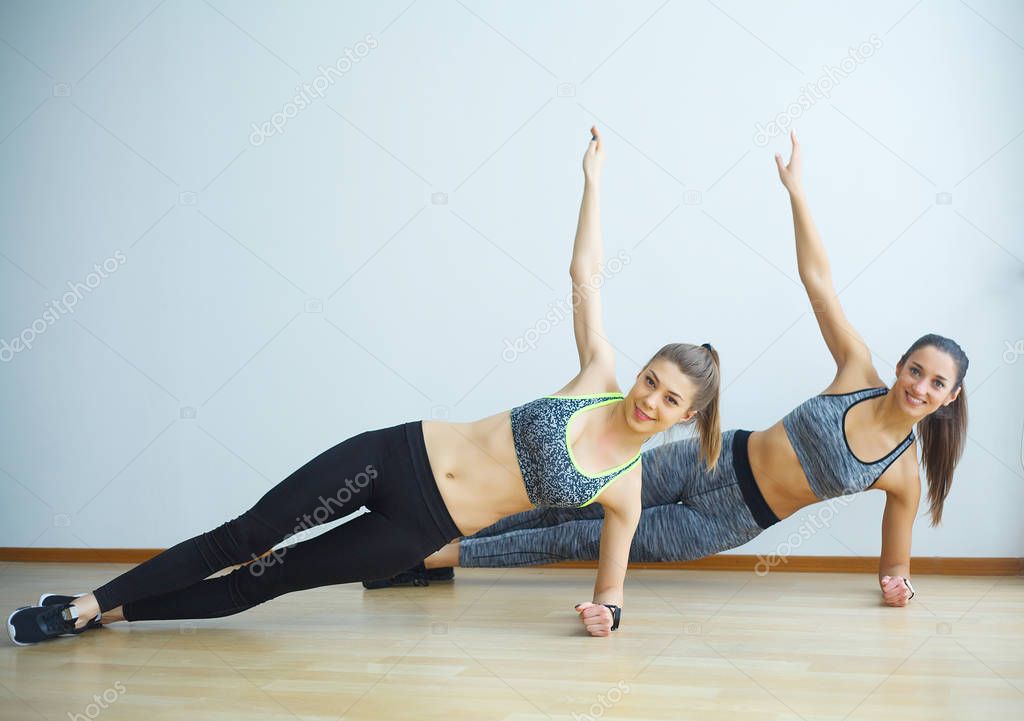 Two sporty girls doing exercises ups in gym