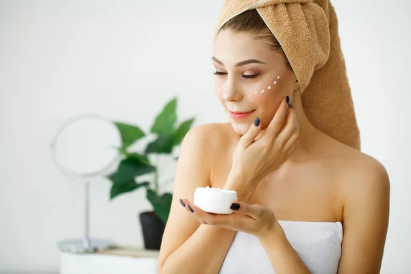 Perawatan kulit. Wanita dengan wajah sehat menerapkan krim kosmetik di bawah — Stok Foto
