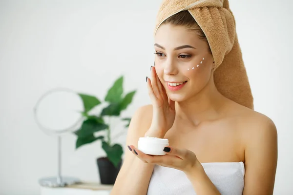 Perawatan kulit. Wanita dengan wajah sehat menerapkan krim kosmetik di bawah — Stok Foto