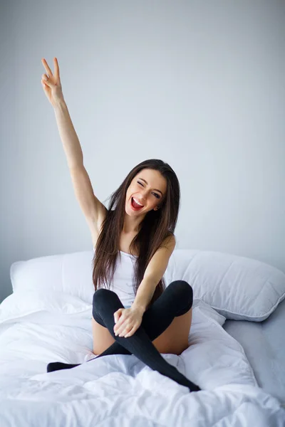 Mulher sorridente com corpo apto e belas pernas na cama branca — Fotografia de Stock