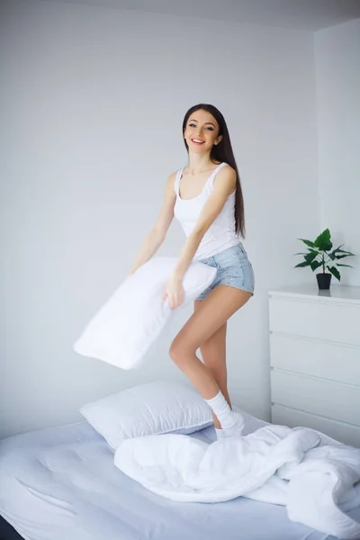 Glad tjej hoppa och ha roligt i sängen — Stockfoto