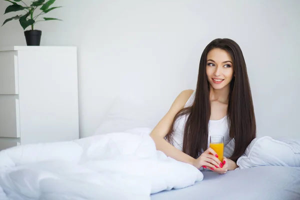 Vrouw drinken sinaasappelsap in slaapkamer — Stockfoto