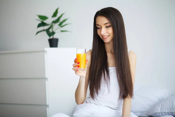 S として朝のオレンジ ジュースのガラスを楽しむ若い女性 — ストック写真