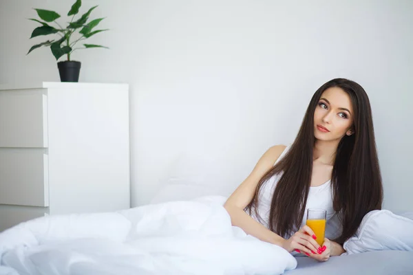 Jonge vrouw genieten van een glas jus d'orange in de ochtend als s — Stockfoto