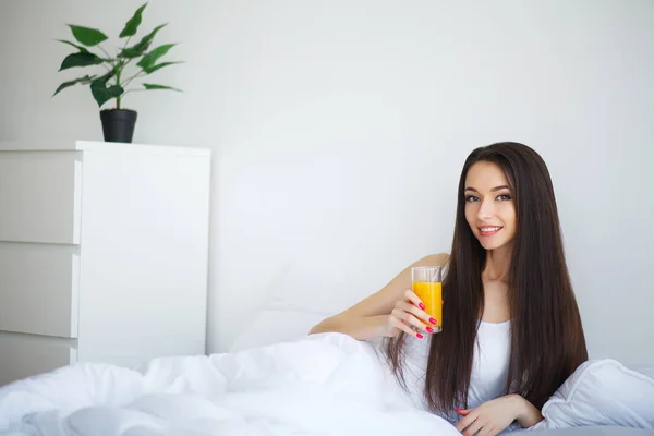Kobieta picie soku pomarańczowego w sypialni — Zdjęcie stockowe