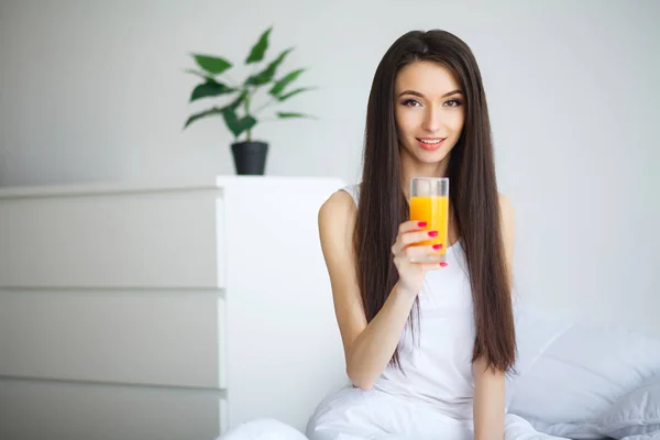 Vrouw drinken sinaasappelsap in slaapkamer — Stockfoto