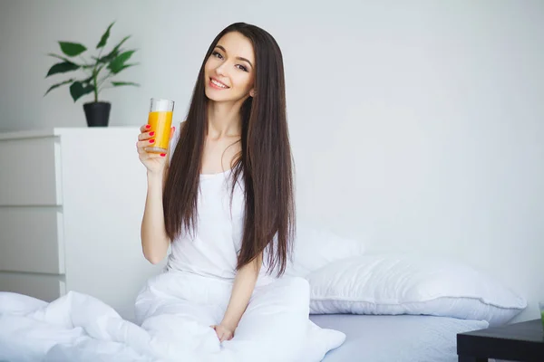 Vrouw drinken sinaasappelsap in slaapkamer — Stockfoto