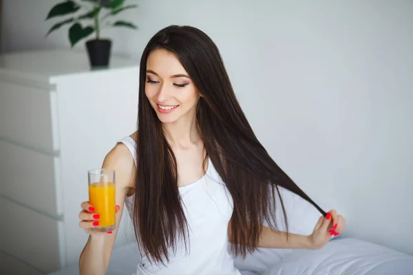 Mladá žena se těší sklenice pomerančové šťávy ráno jako s — Stock fotografie