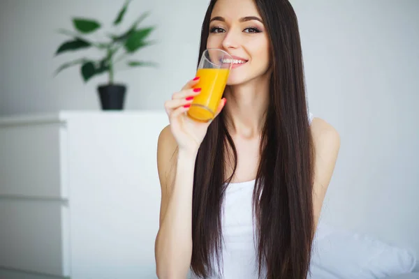 Ung kvinna njuter av ett glas apelsinjuice på morgonen som s — Stockfoto