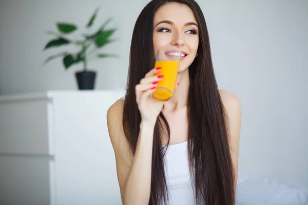 Mulher sorridente casual segurando um copo de suco de laranja — Fotografia de Stock
