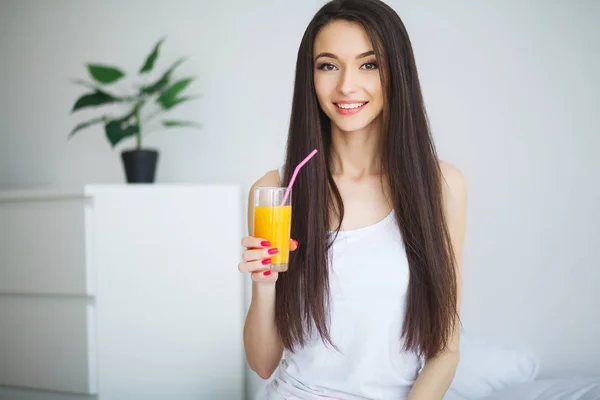 Casual leende kvinna håller ett glas apelsinjuice — Stockfoto