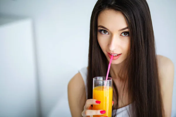 Mulher sorridente casual segurando um copo de suco de laranja — Fotografia de Stock
