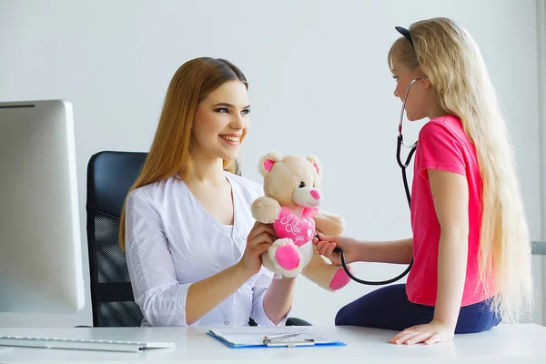 Guapo doctor examinando pequeña niña con estetoscopio —  Fotos de Stock