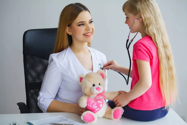 Schöne Ärztin untersucht kleines Mädchen mit Stethoskop — Stockfoto