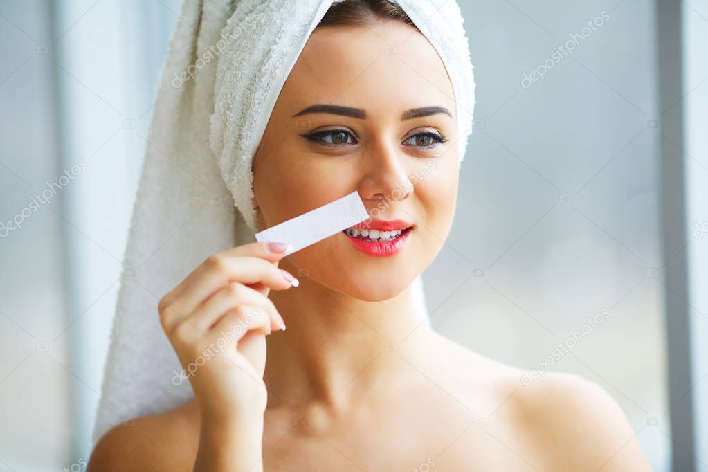 Young beautiful woman makes wax eyelids in her bathroom.