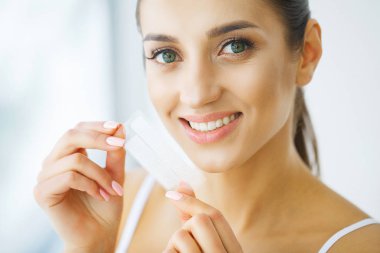 Diş beyazlatma. Şerit beyazlatma tutan güzel gülümseyen kadın