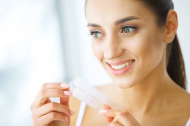 Diş beyazlatma. Şerit beyazlatma tutan güzel gülümseyen kadın