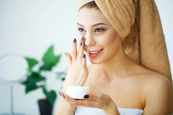 Una mujer hermosa usando un producto para el cuidado de la piel, crema hidratante o loti — Foto de Stock
