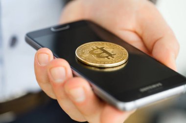 Bitcoin konsepti ile akıllı telefon ekranında tutan el.