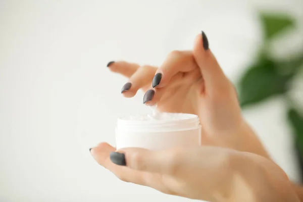Crème voor het gezicht of lichaam in witte container op vrouwelijke handen — Stockfoto